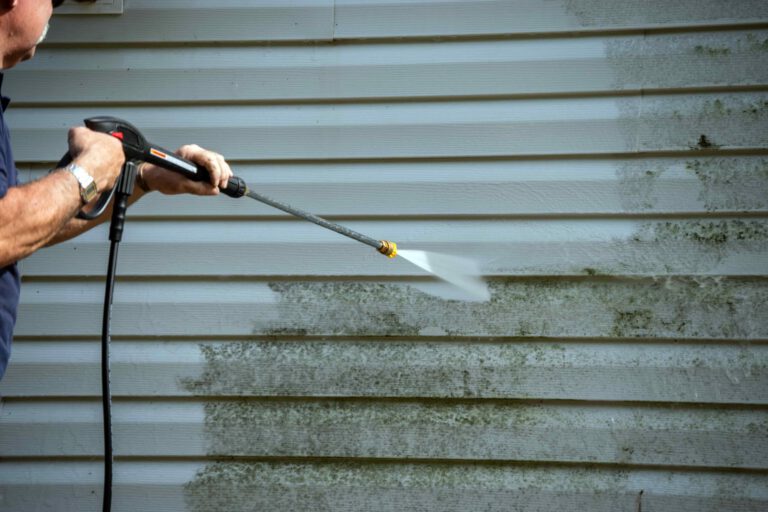 Power washing exterior siding for deep cleaning.