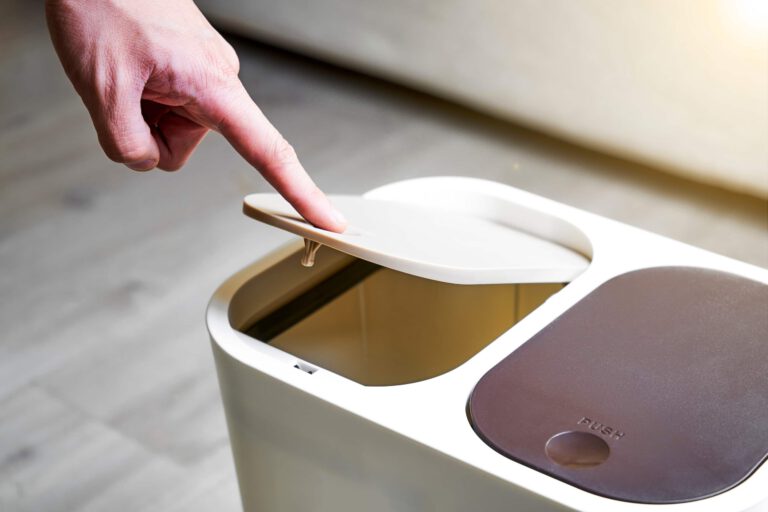 Smart trash bin being cleaned with a finger pointing at the lid.