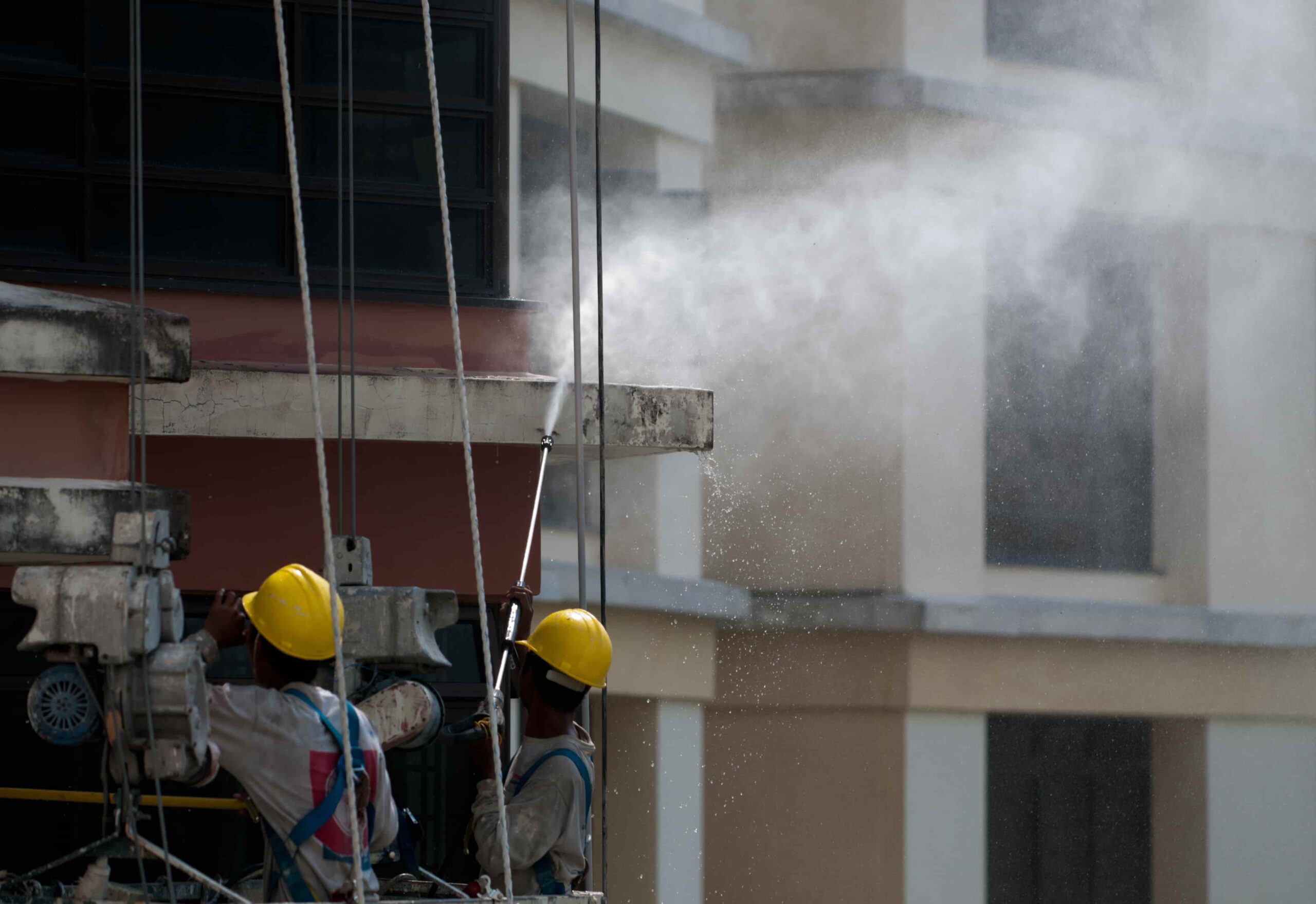 damage restoration team cleaning smoke and soot from building exterior.