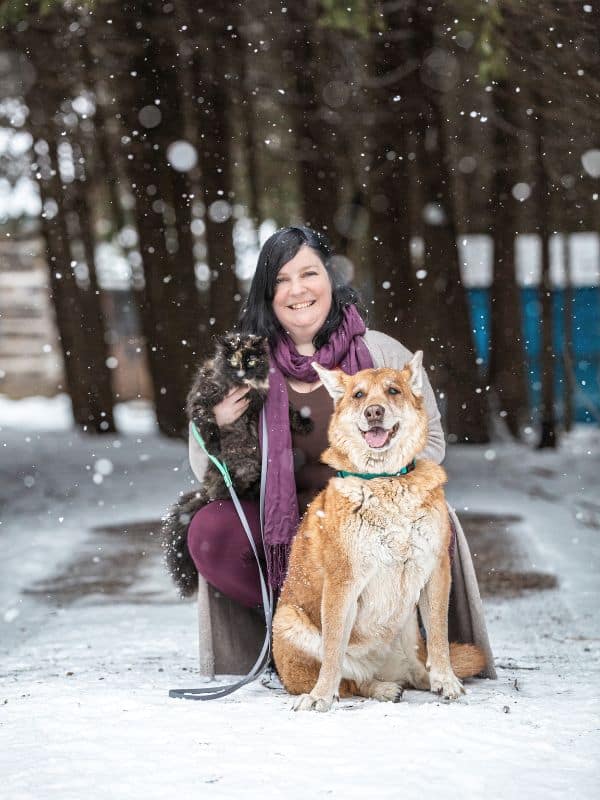 woman sitting outside with a dog and a cat