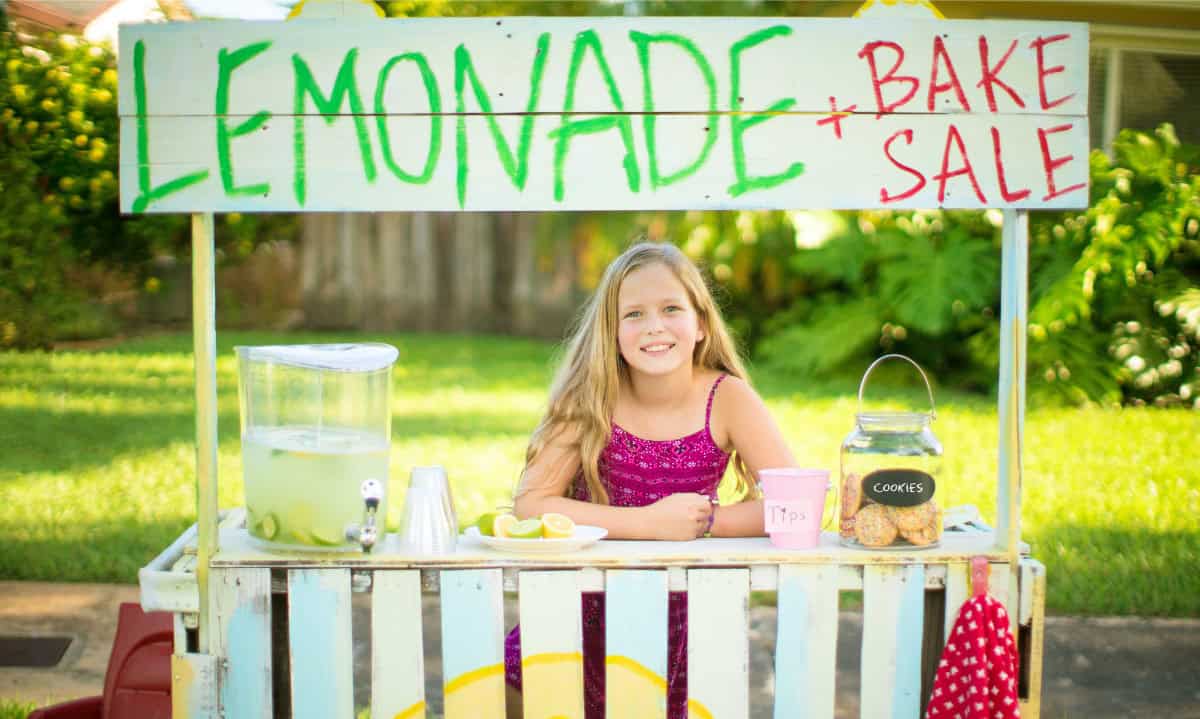 young girl sitting at a lemonade stand | Meaningful Ways to Involve Your Children in Supporting Animal Rescue Efforts