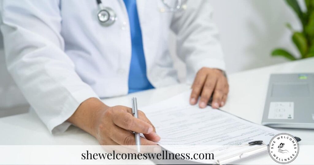Close-up of a doctor in a white coat writing on a clipboard in an office. A laptop and plant are visible. The mood is professional and focused.