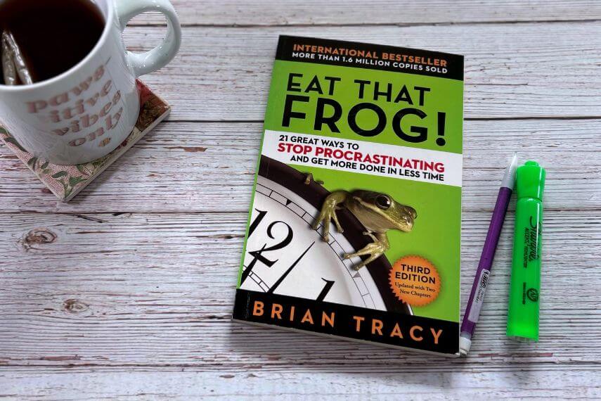 Eat That Frog book, highlighter, pencil, and cup of tea