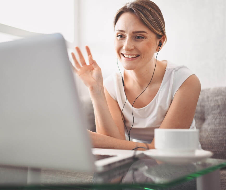 woman with earbuds waving during a virtual consultation call