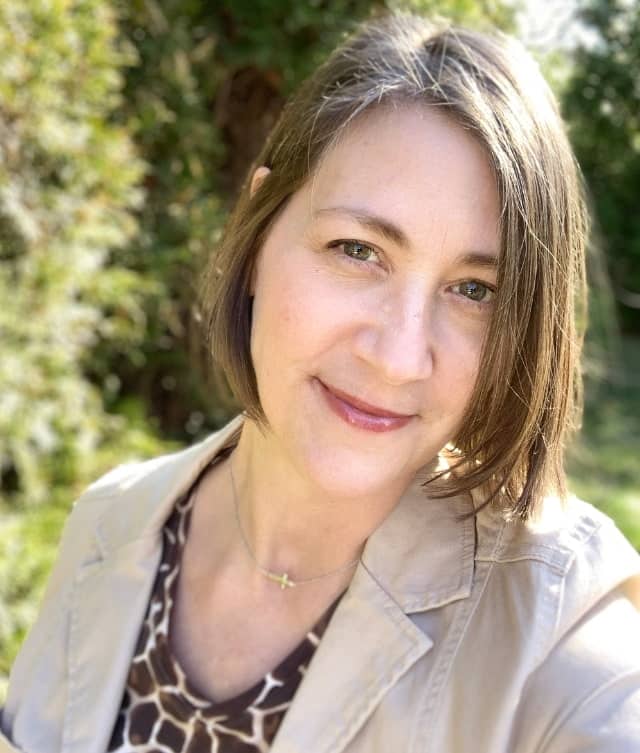 Tina, she welcomes wellness, headshot outside with green foliage