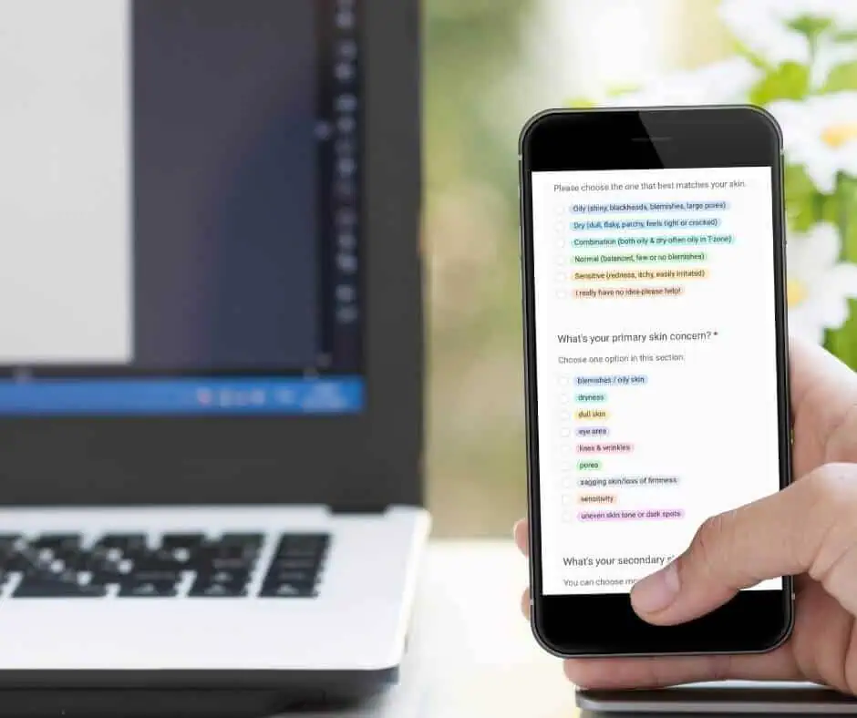 woman holding mobile phone and taking skincare quiz, computer in background