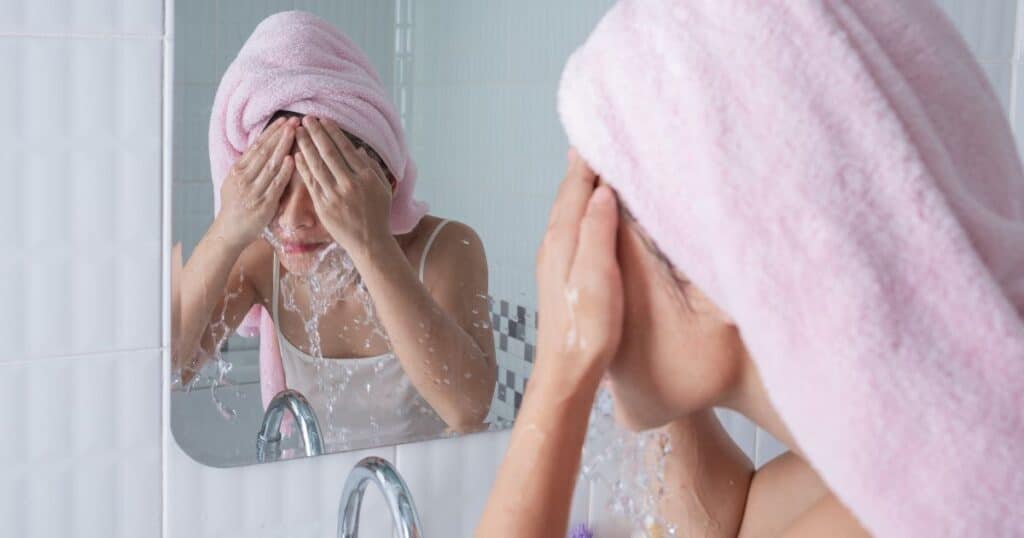 woman washing her face at bathroom sink