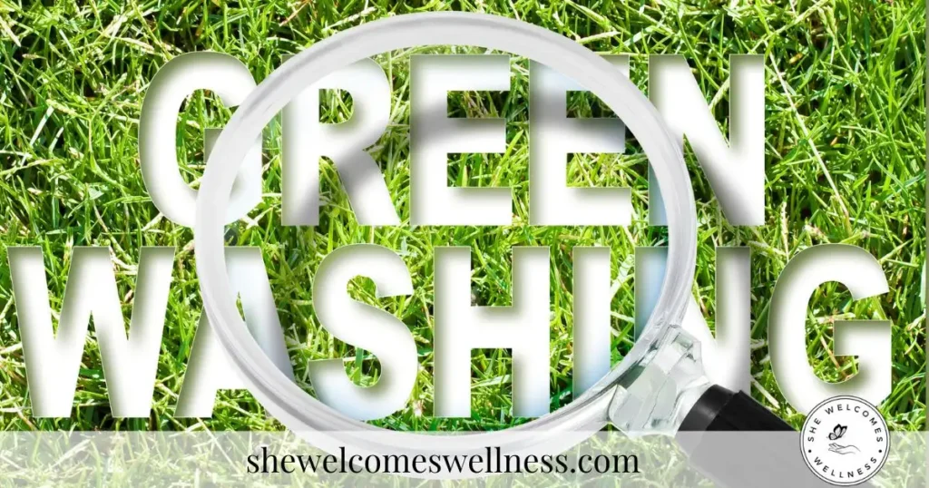 The image shows the word "GREENWASHING" on grass with a magnifying glass over some of the letters. Website URL "shewelcomeswellness.com" and logo are at the bottom.