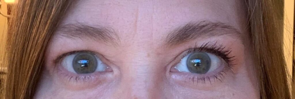 Before-and-after photo of Tina’s eyes — one side without any makeup, and the other side with Counter mascara and brow gel applied, showing fuller lashes and defined brows.