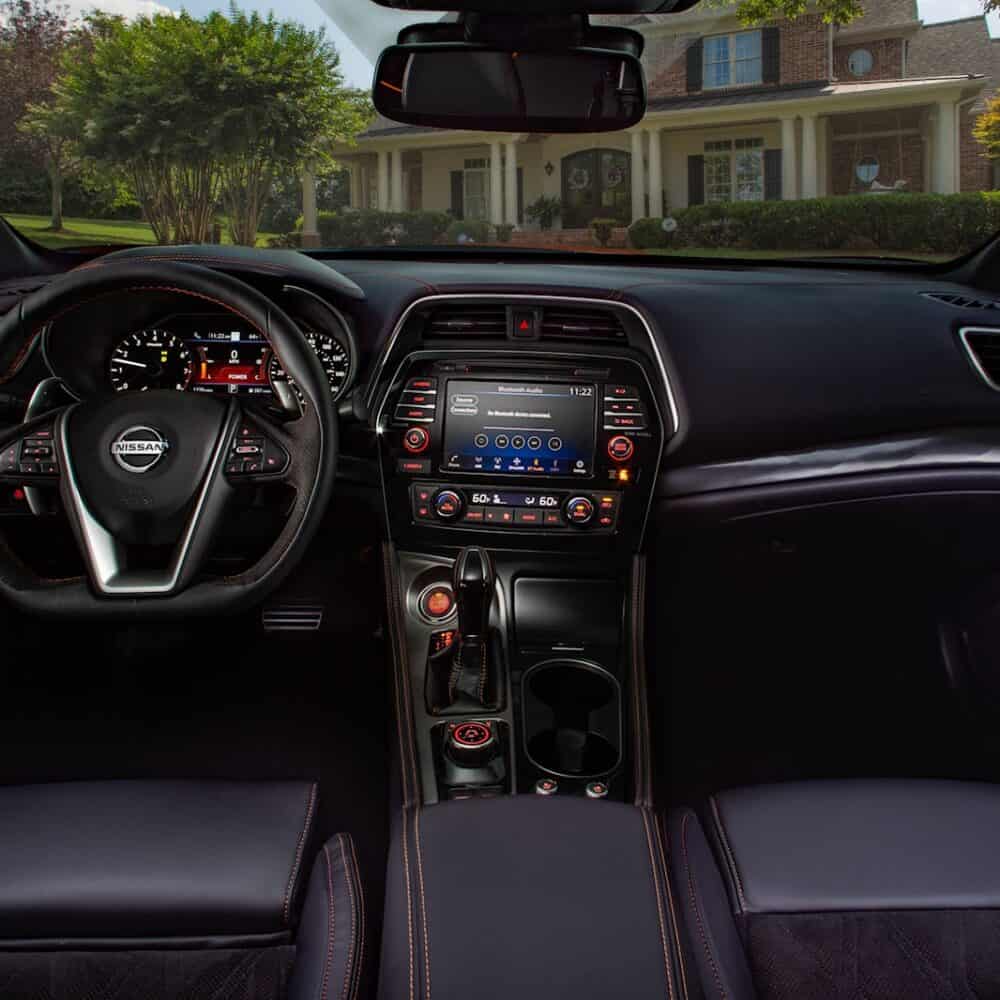 Interior dashboard and steering wheel of Nissan Maxima with custom accessories.