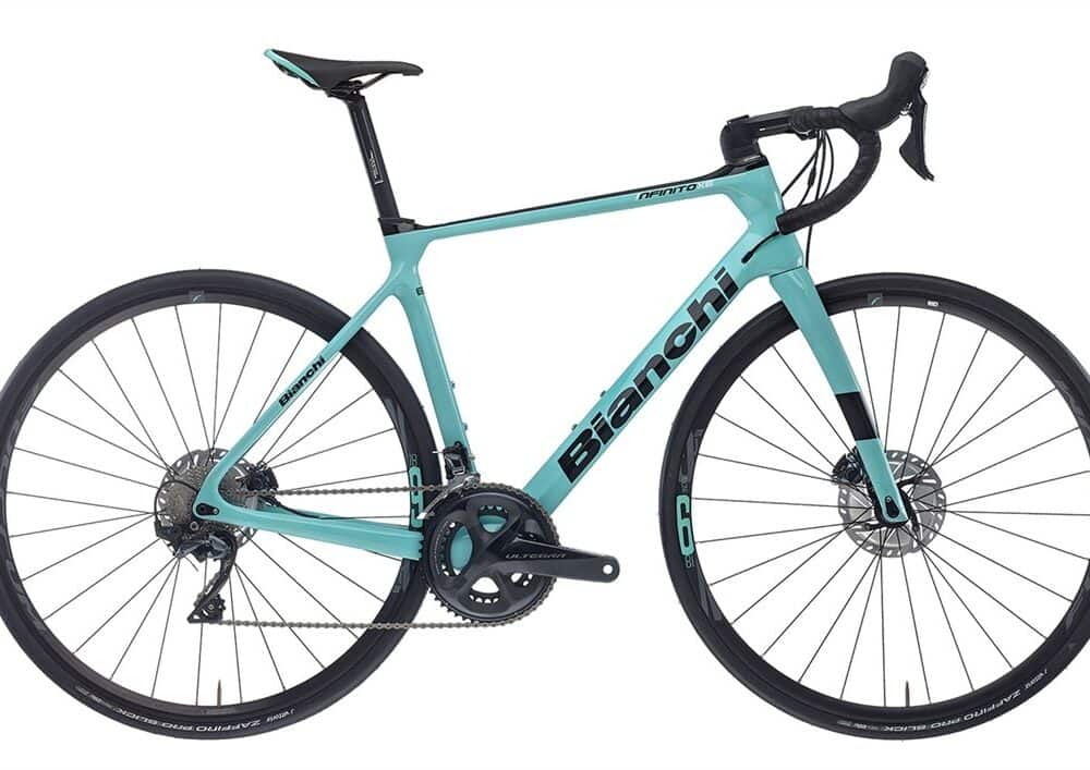 Light blue Bianchi road bike with carbon frame and drop handlebars for road cycling.