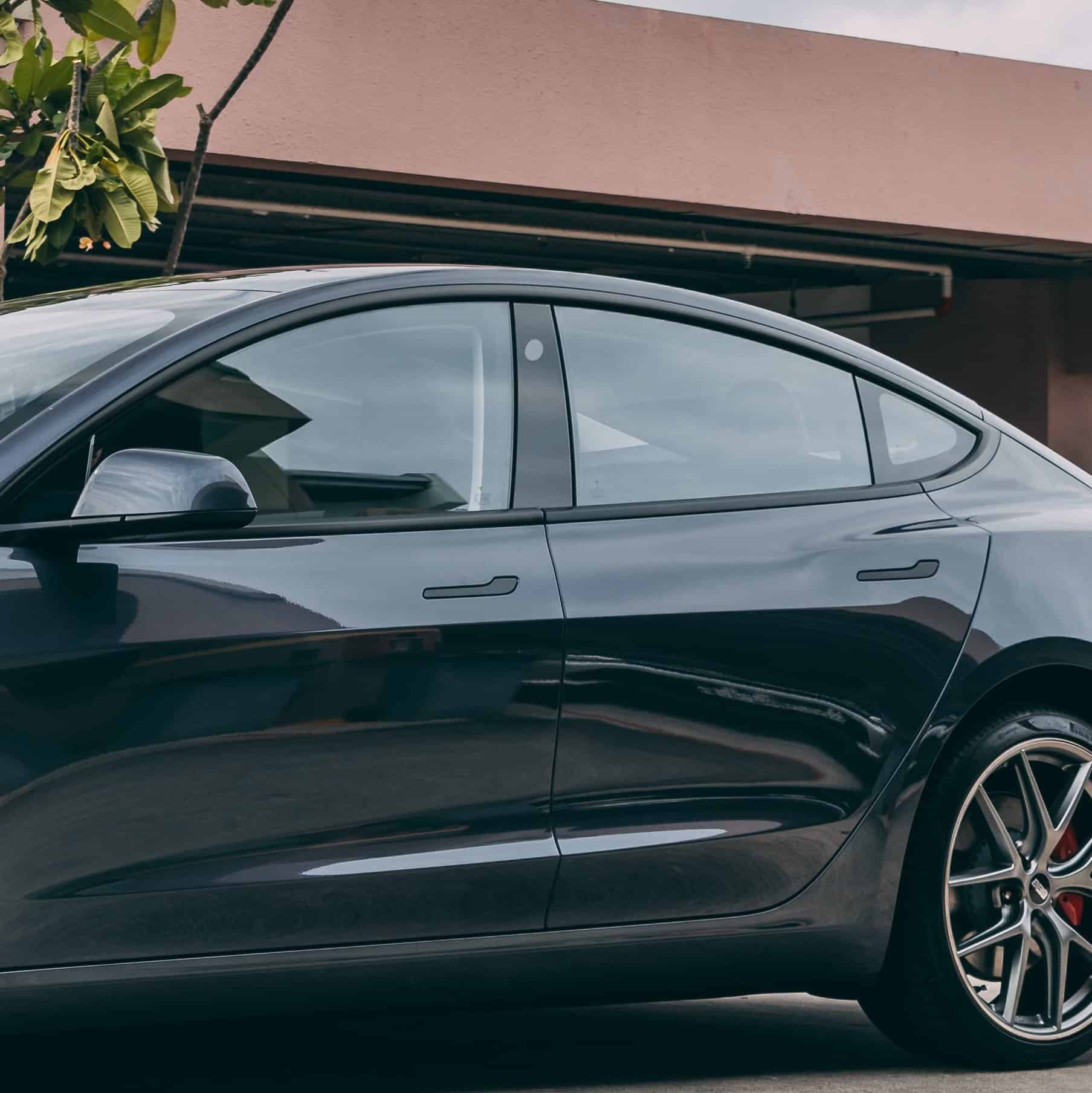 Black Tesla Model 3 electric vehicle parked outdoors, showcasing sleek design and modern features.