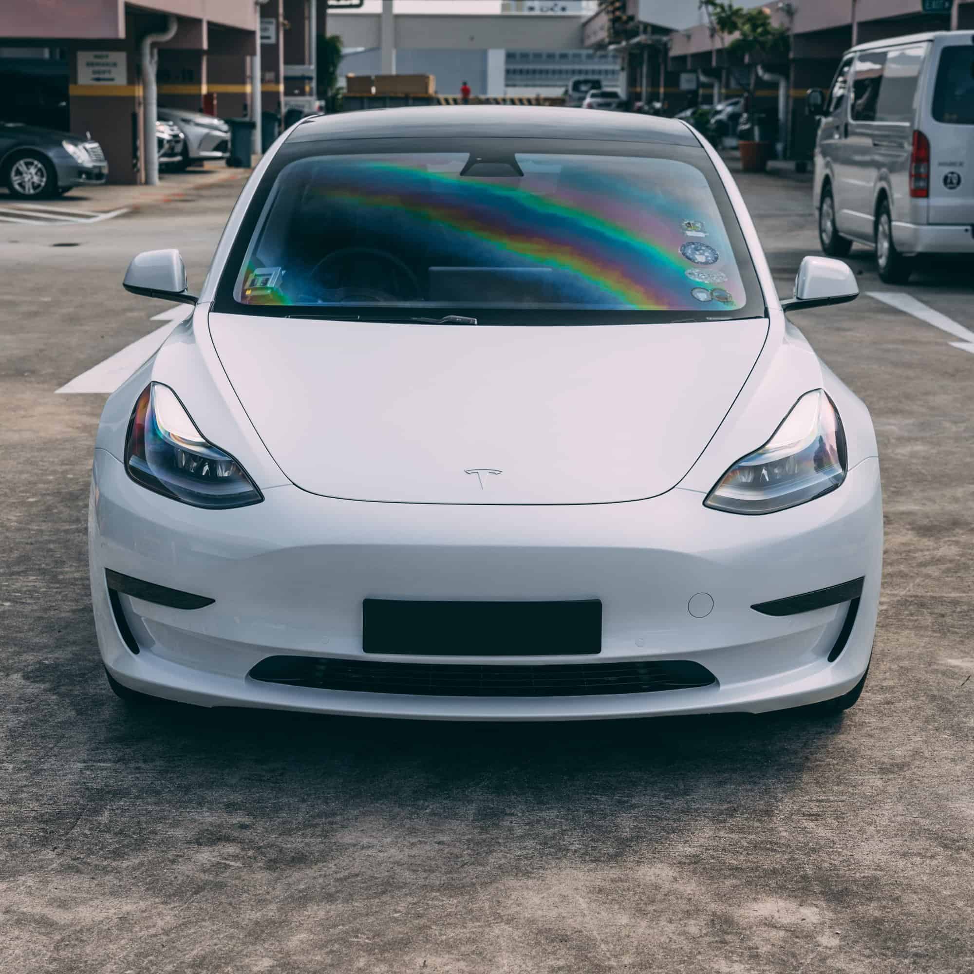 White Tesla Model 3 electric vehicle parked outdoors in a parking lot.