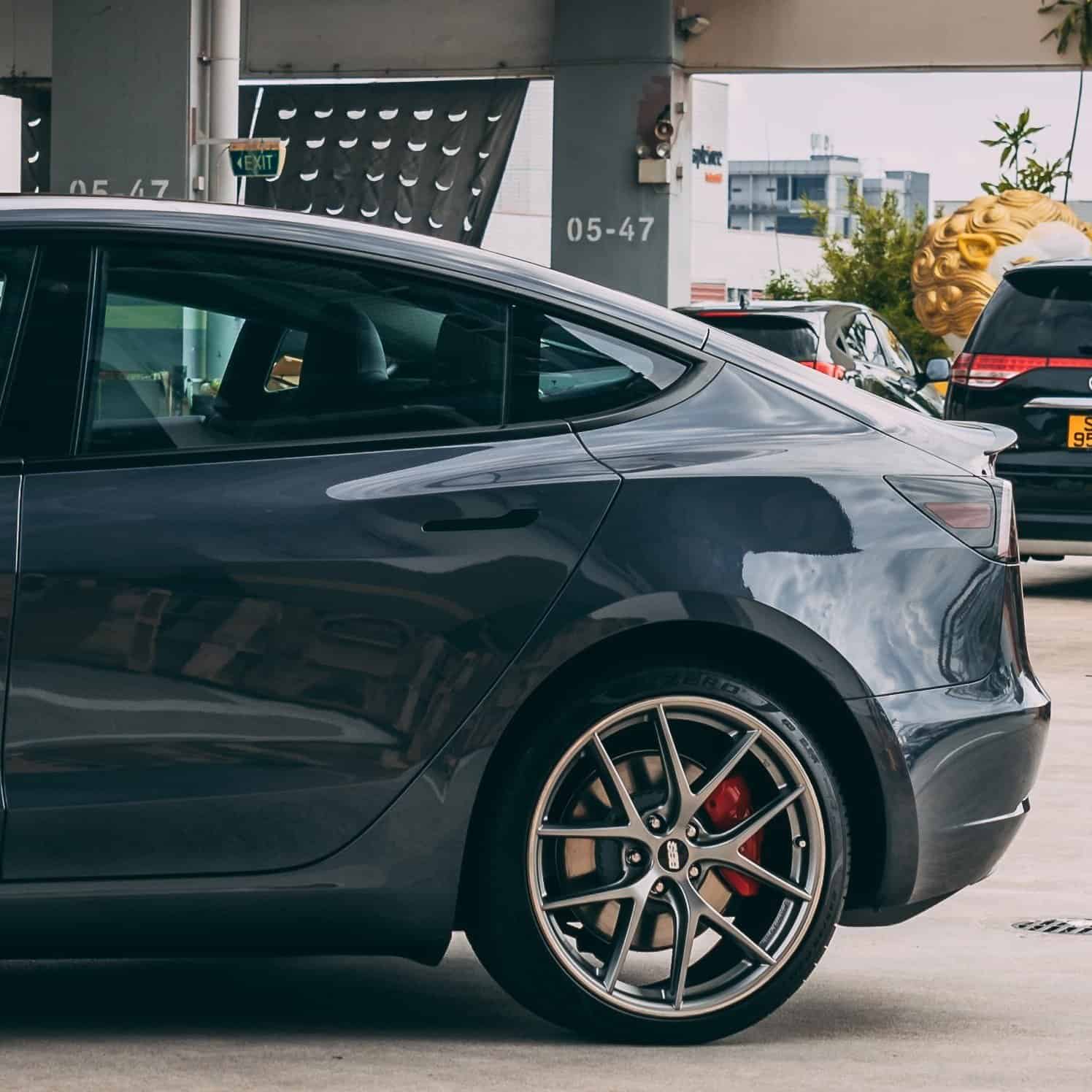 Tesla Model 3 electric car rear side view in a parking lot.
