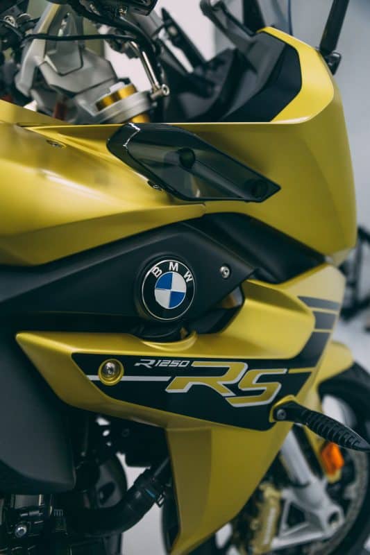 BMW R1250 RS motorcycle with yellow finish, featuring sleek styling and performance-oriented details.