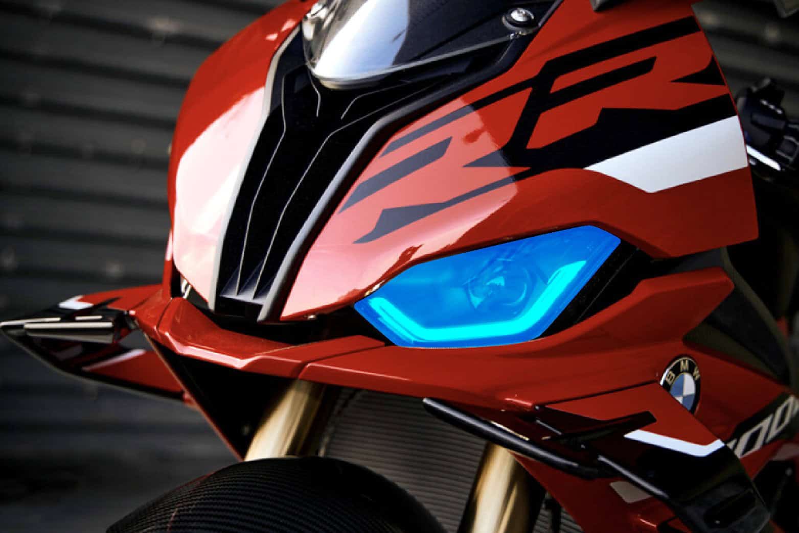 Close-up of a sleek red motorcycle featuring a vibrant blue headlight and modern design elements.