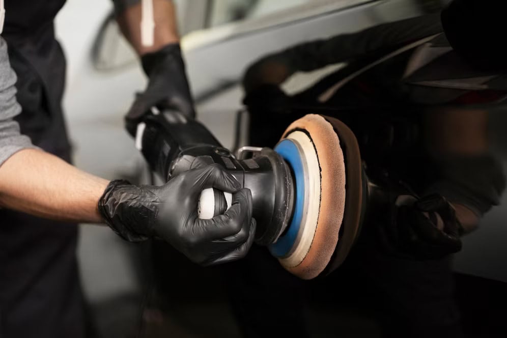 Technician polishing car with buffer during pre-PFF detailing process.