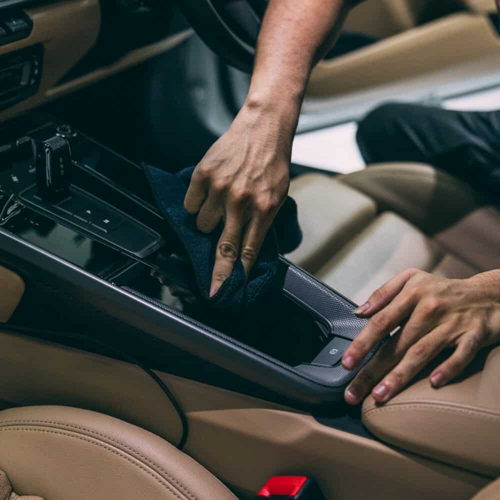 Technician applying protective coating to car interior for detailing and protection.