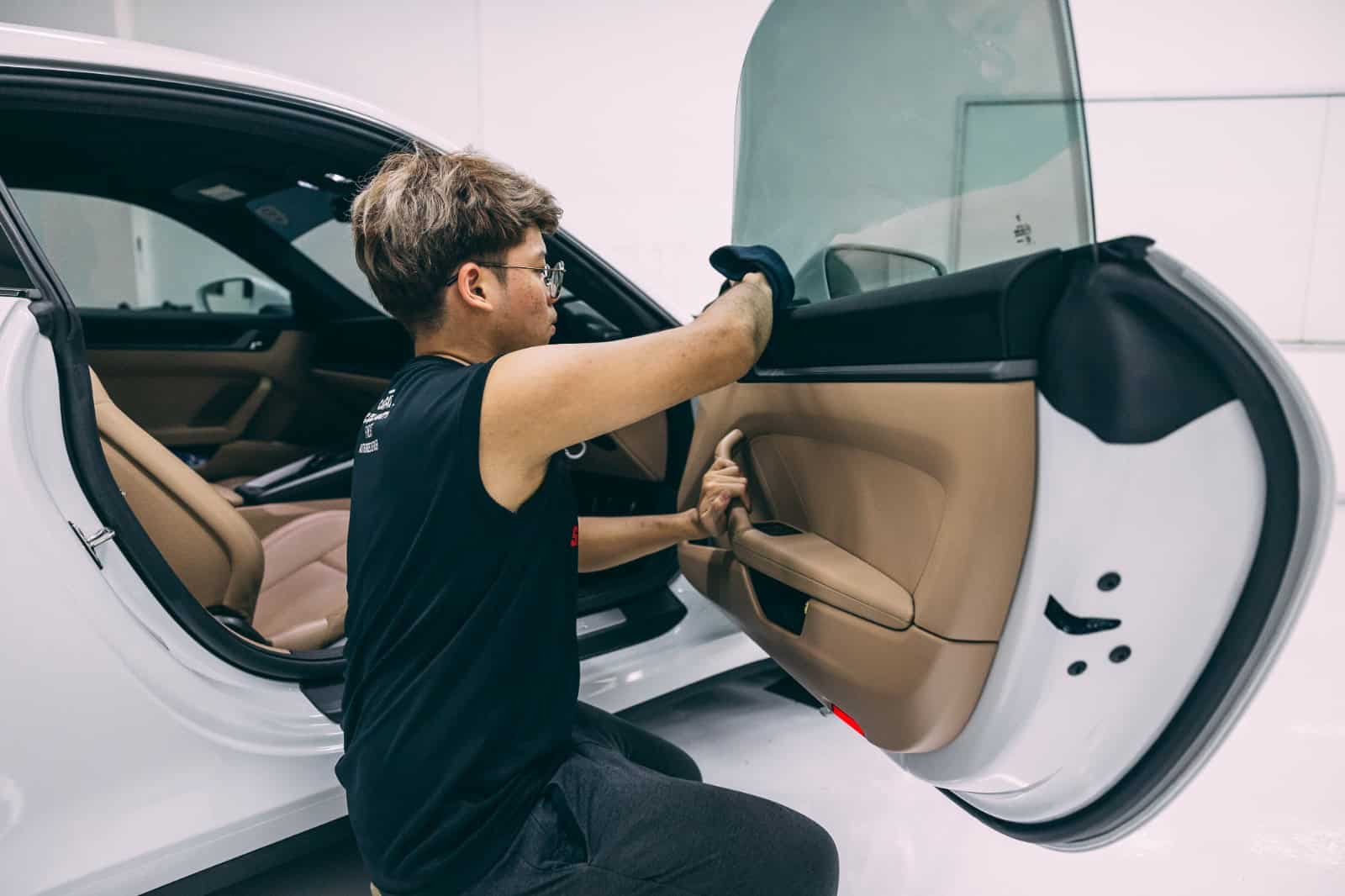 Technician applying protective coating to car door interior during detailing process.