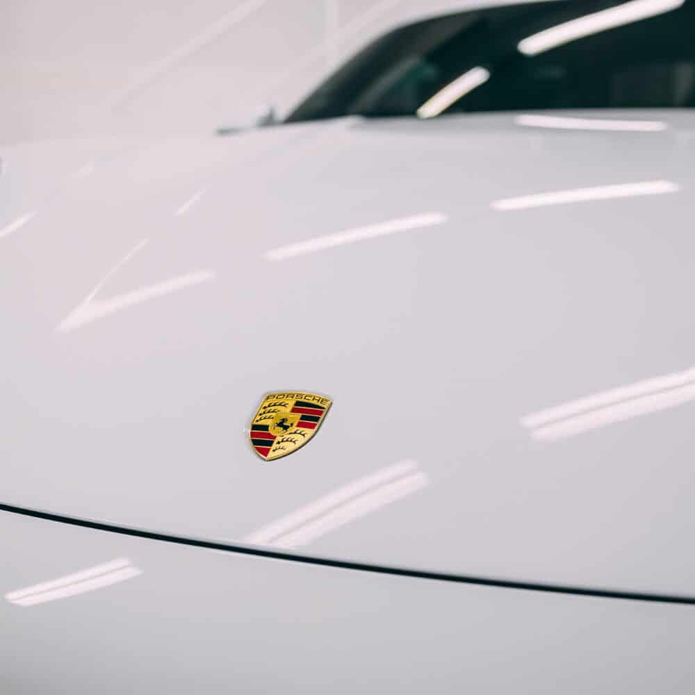 Close-up of a white Porsche with detailed paintwork and logo.
