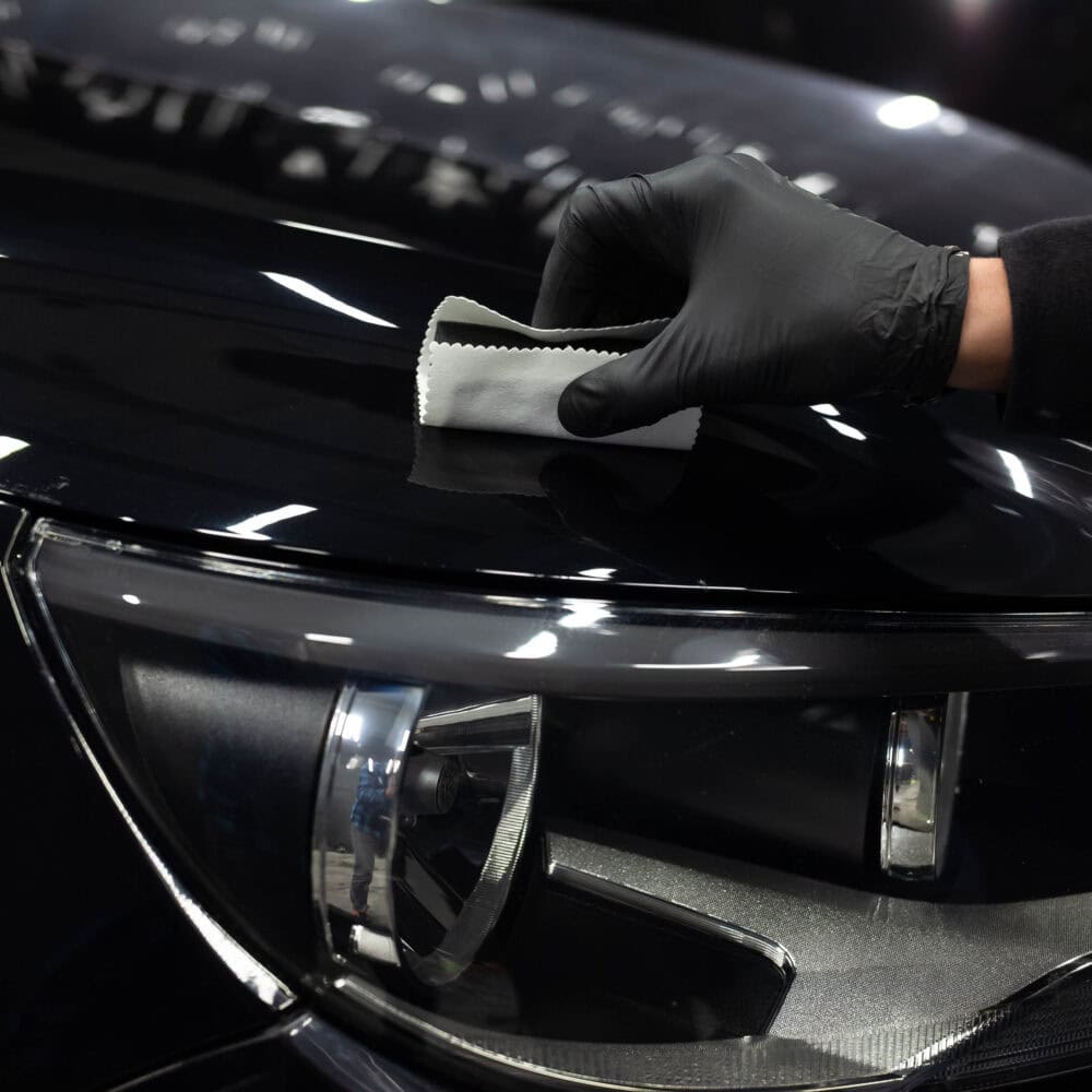 Protective film being applied to a car's hood for enhanced gloss and scratch resistance.