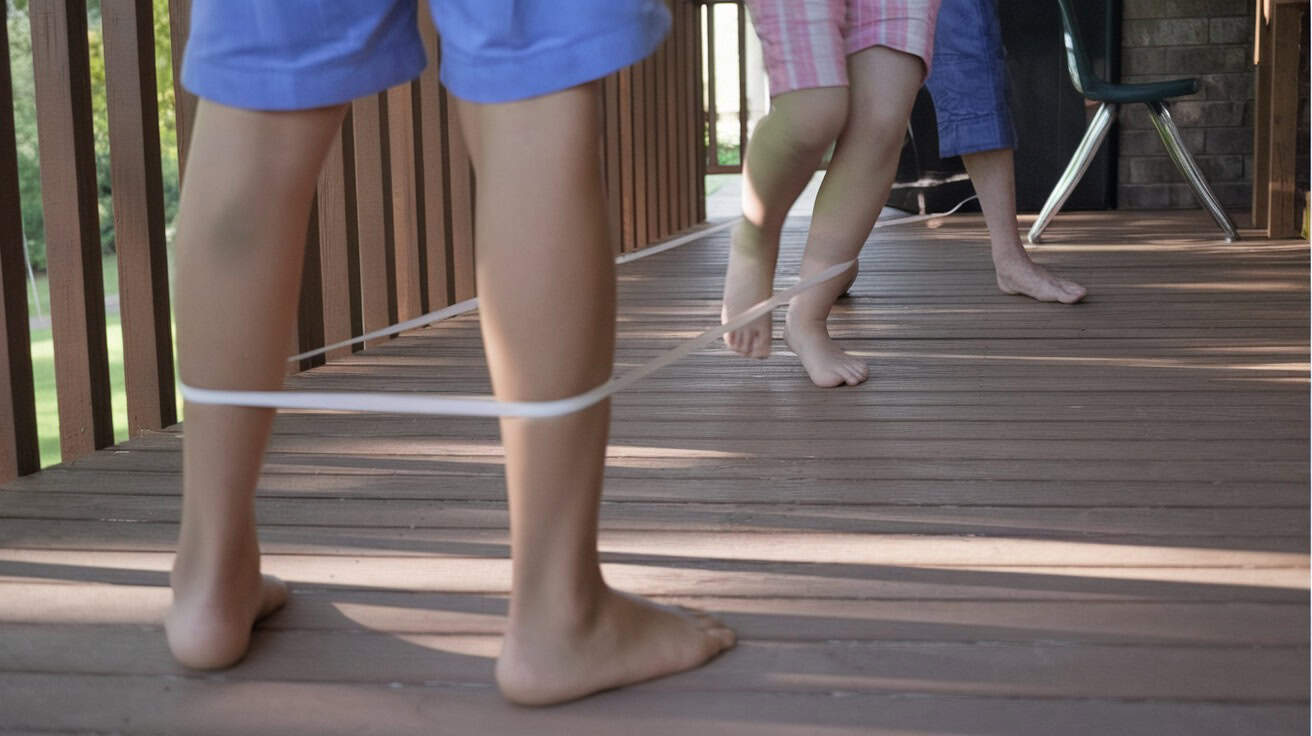 Playground Games Every Boomer Mastered That Kids Today Never Heard Of 6 A group of kids playing Chinese Jump Rope, a popular 1960s playground game.