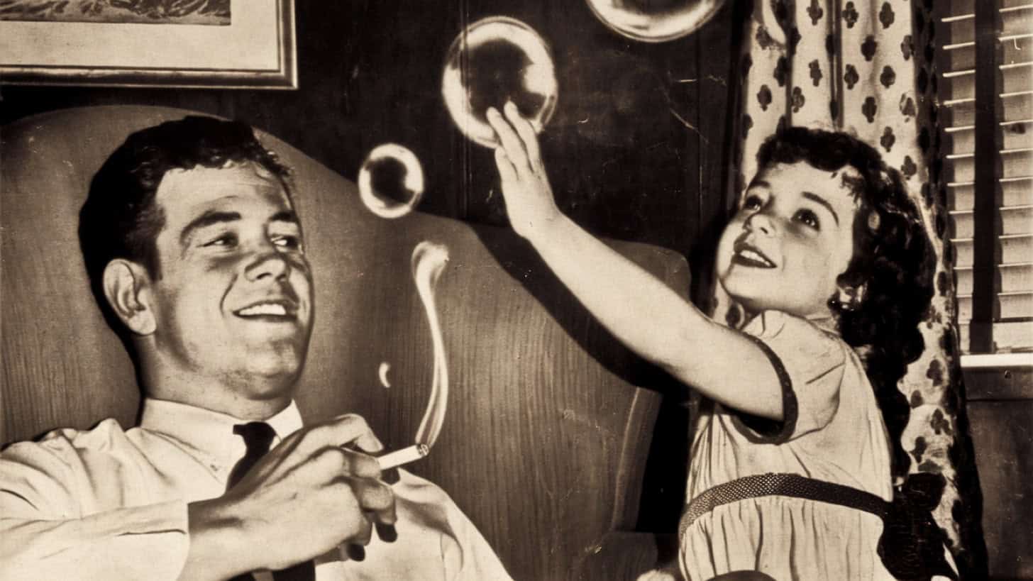 Image of a parent smoking near children, highlighting 60s parenting practices.