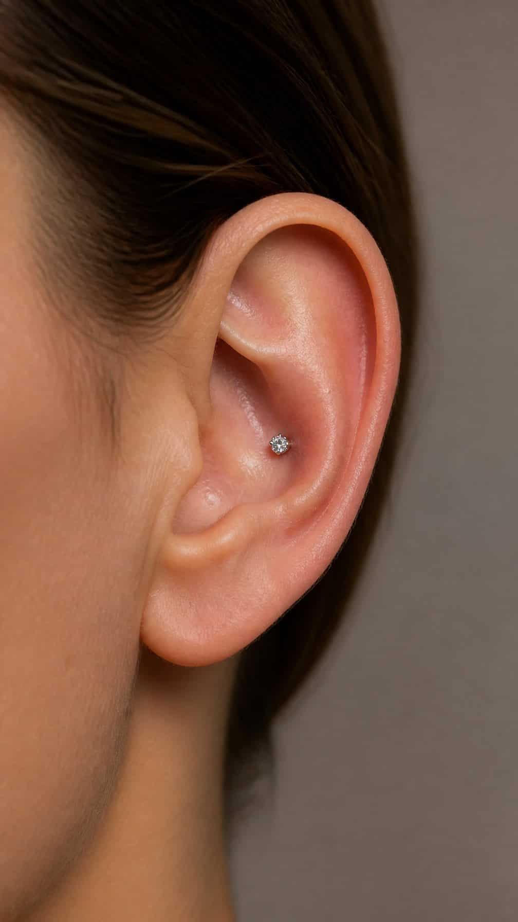 Close-up of an ear wearing a small white gold diamond conch stud.