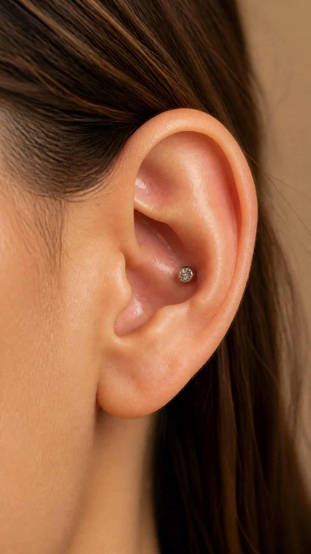 Close-up of an ear wearing a small silver conch stud.