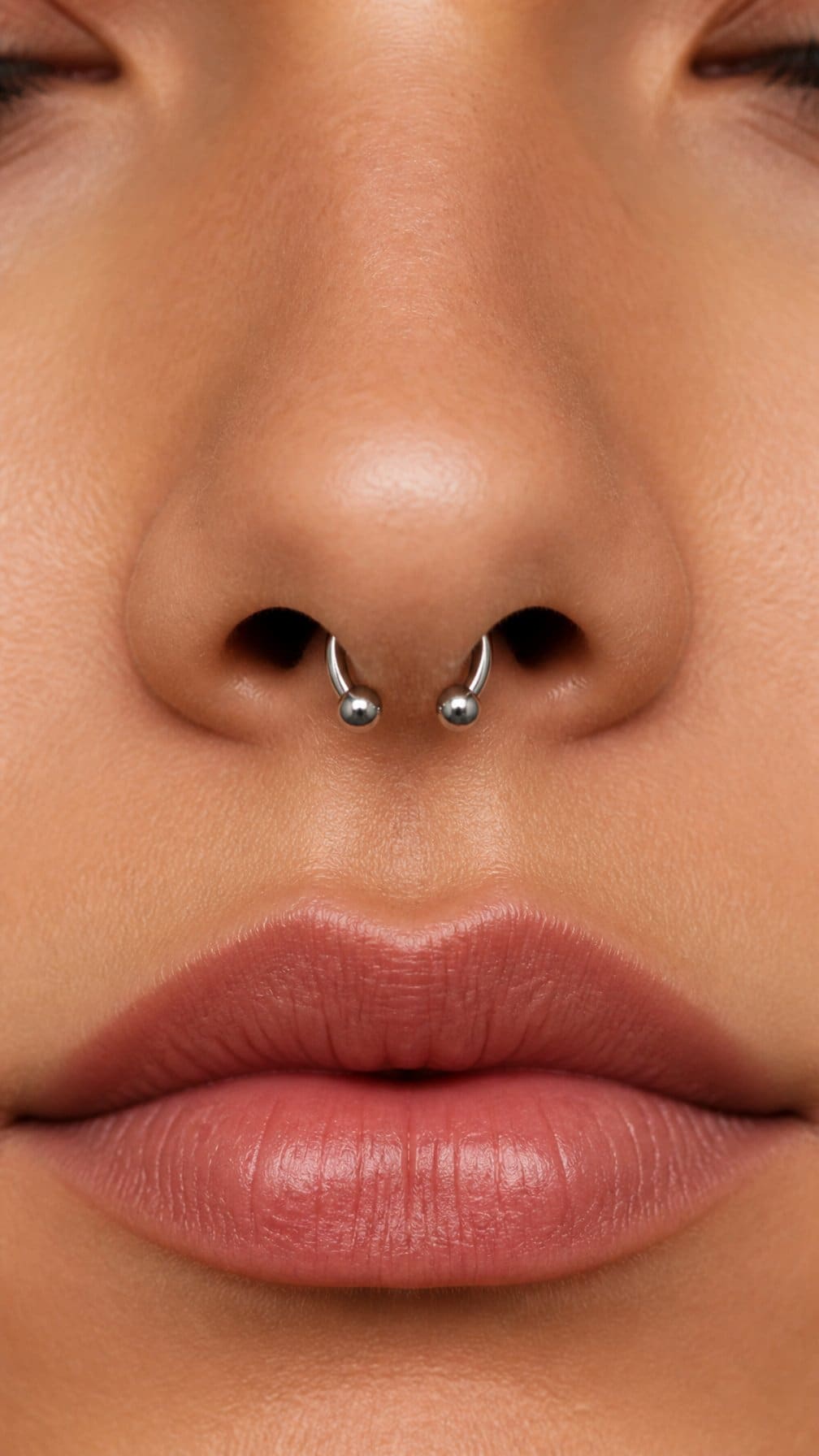 Close-up of a person wearing a beaded circular barbell septum piercing.