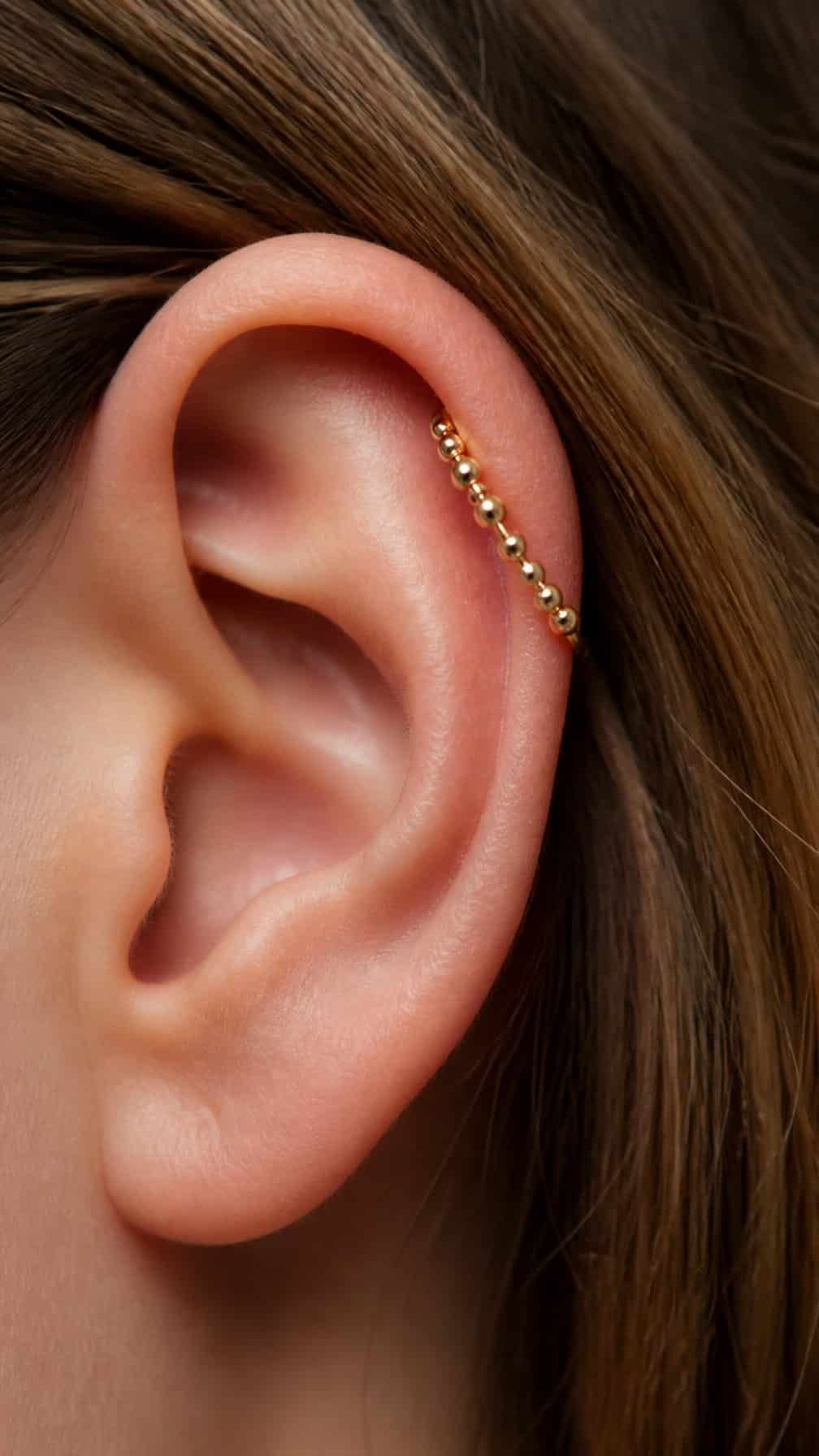 Close-up of an ear wearing a beaded hoop in the upper cartilage.