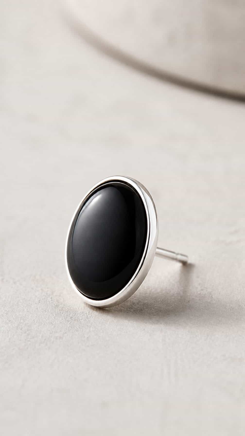 A polished black onyx conch cabochon earring resting on a neutral surface.
