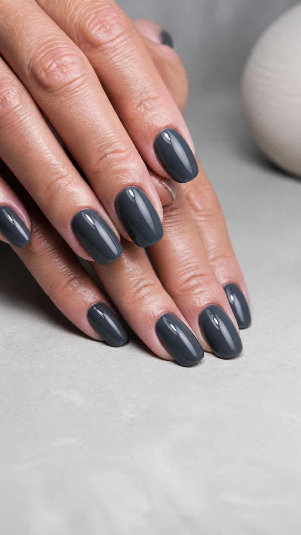 Close-up of mature hands with glossy charcoal gray manicured nails.