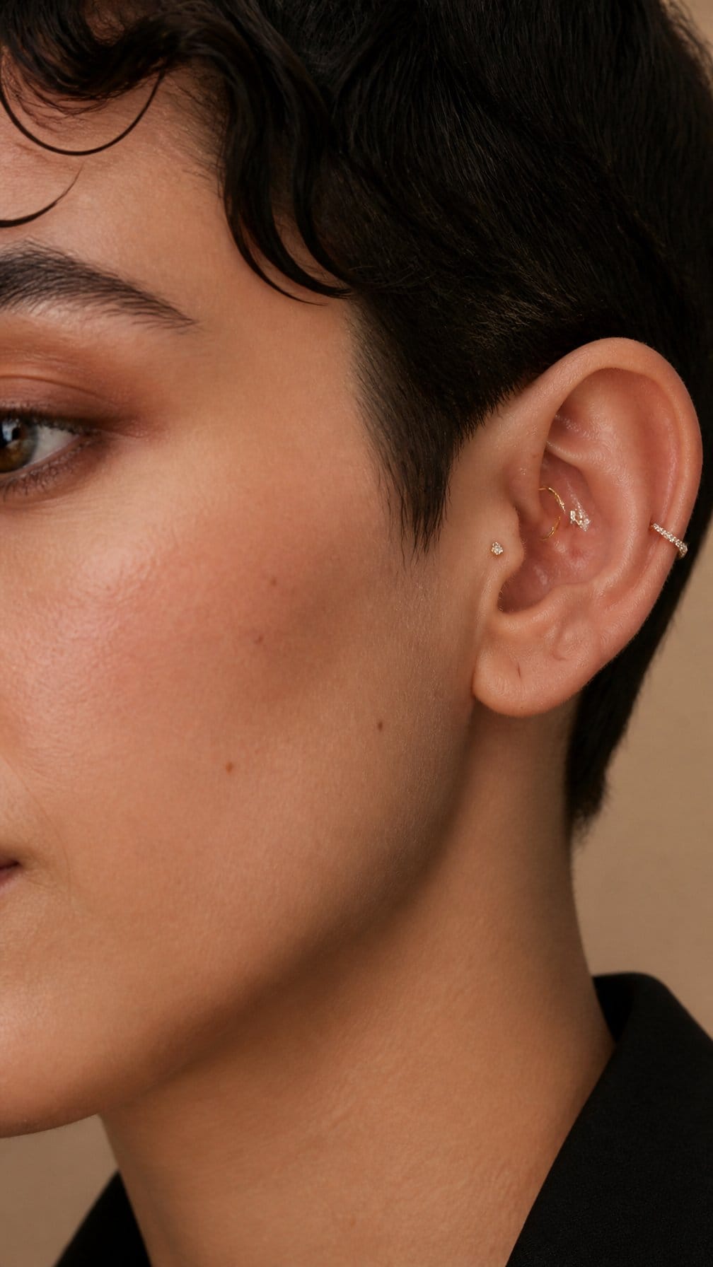 Close-up of an ear displaying several elegant conch piercings with gold and silver jewelry.