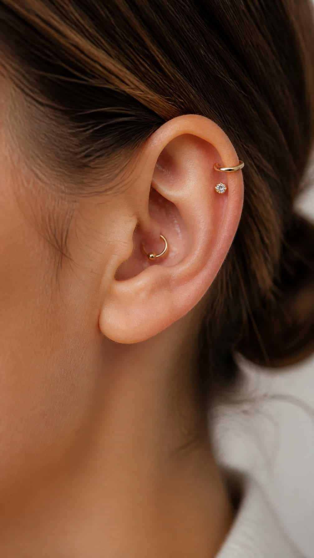 Close-up of an ear with balanced conch and helix piercings.