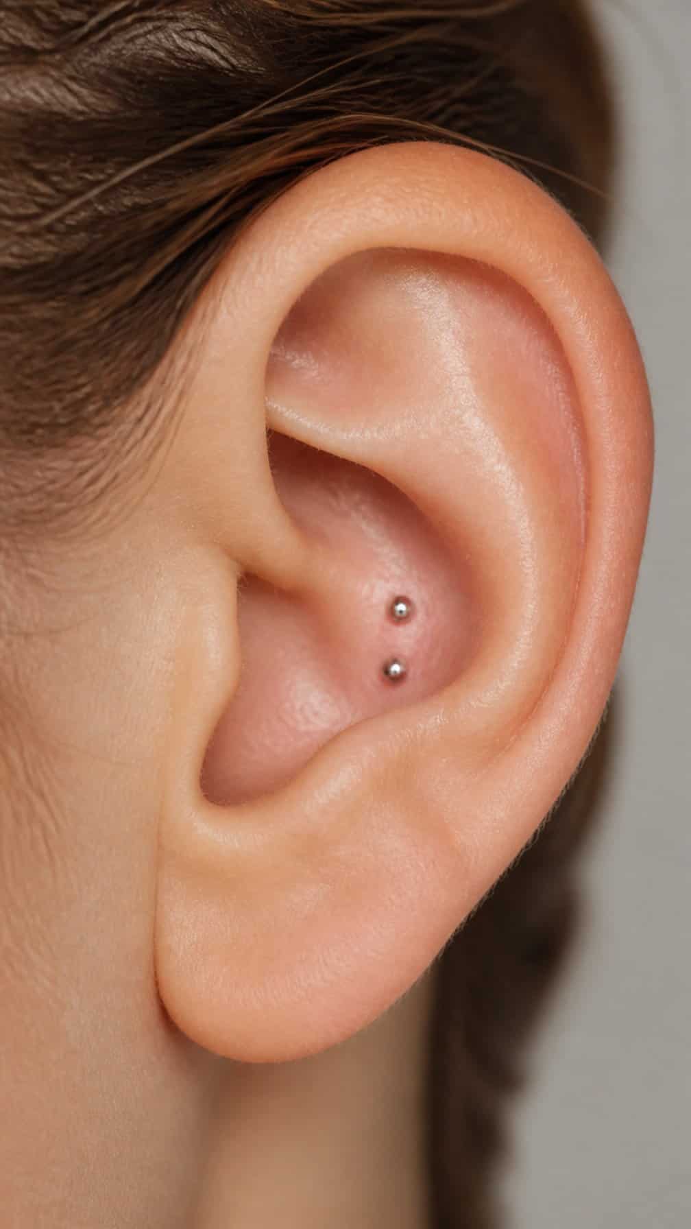Close-up of an ear with two small studs arranged in the conch area.