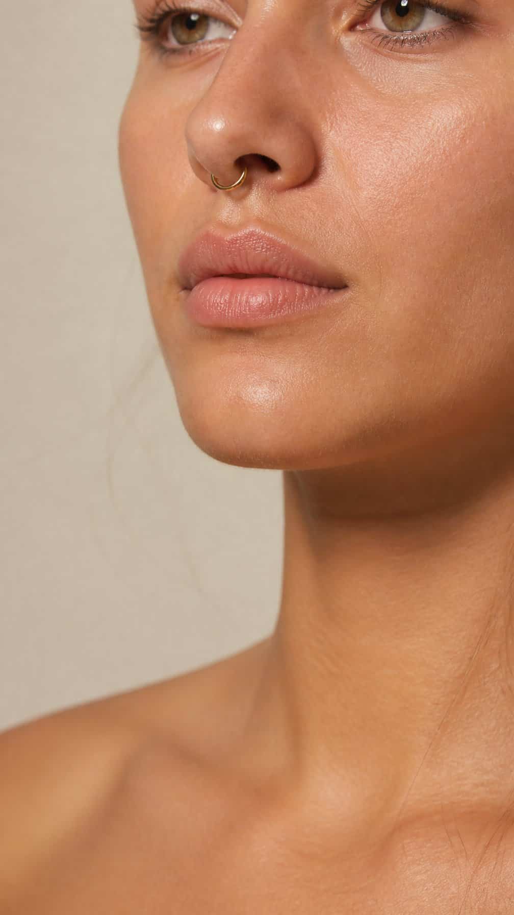 Close-up of a person wearing a delicate gold septum ring.
