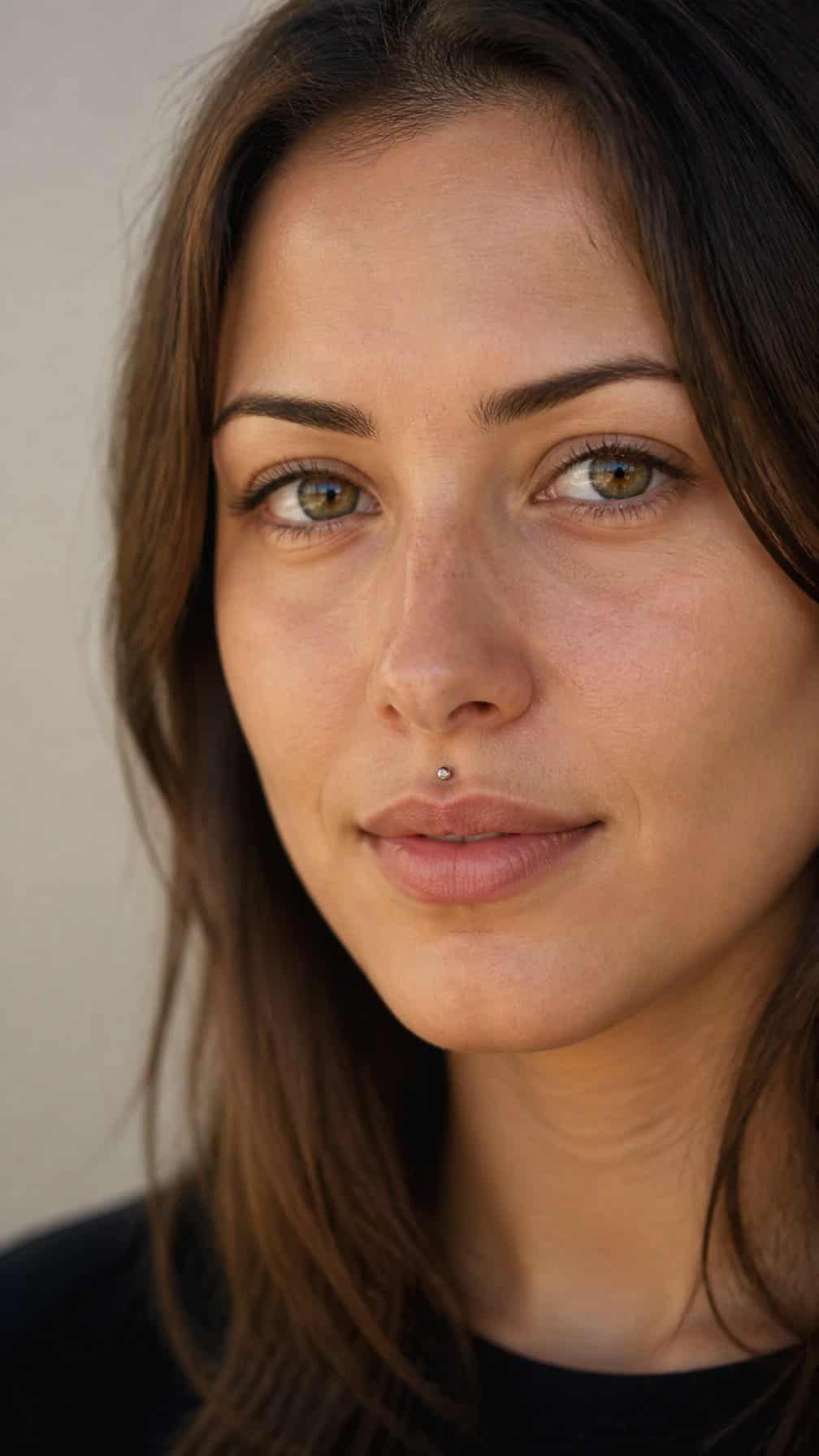 Close-up portrait of a woman wearing a small philtrum stud piercing above her upper lip.