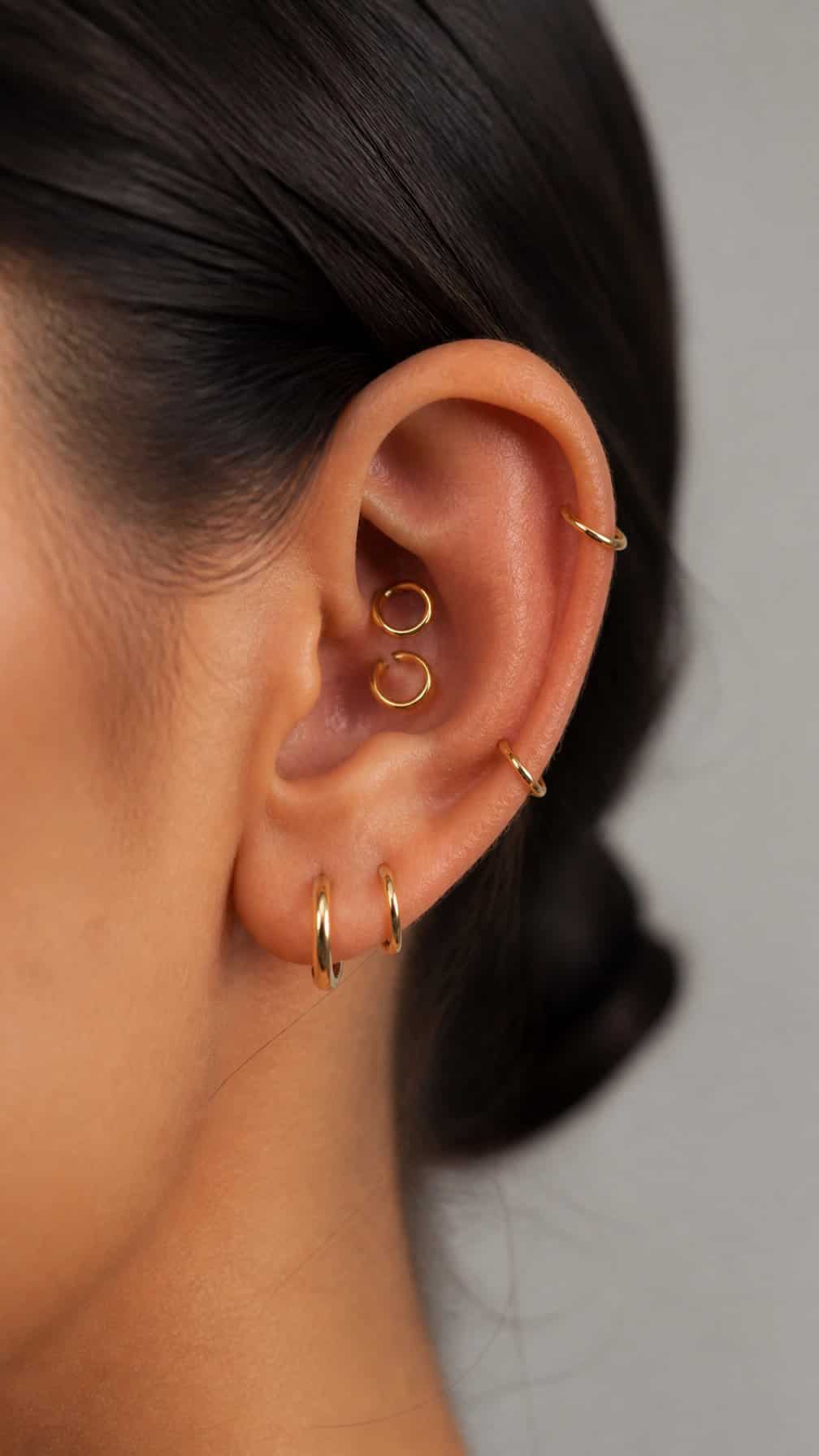 Close-up of an ear with two inner cartilage hoop piercings and matching outer hoops.