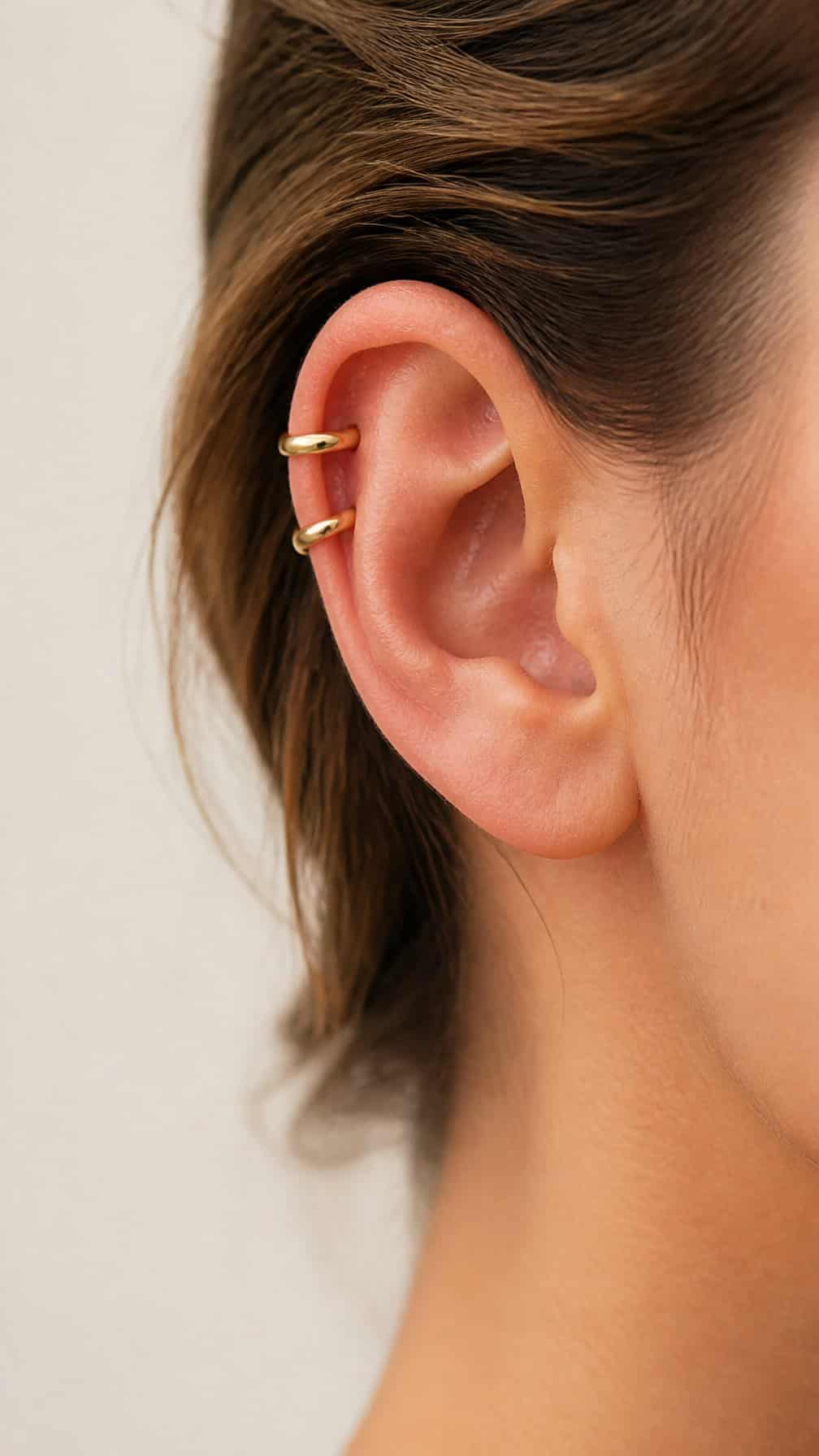 Close-up of an ear with two matching hoops along the upper cartilage.