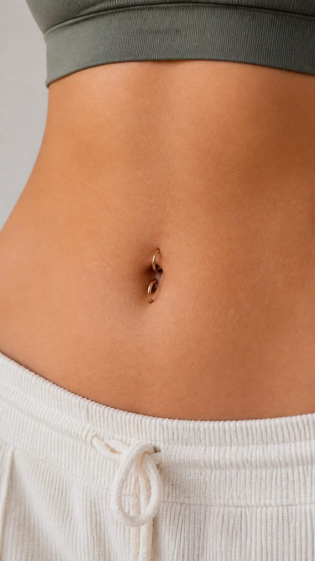 Close-up of an adult midriff wearing a double hoop belly button ring.