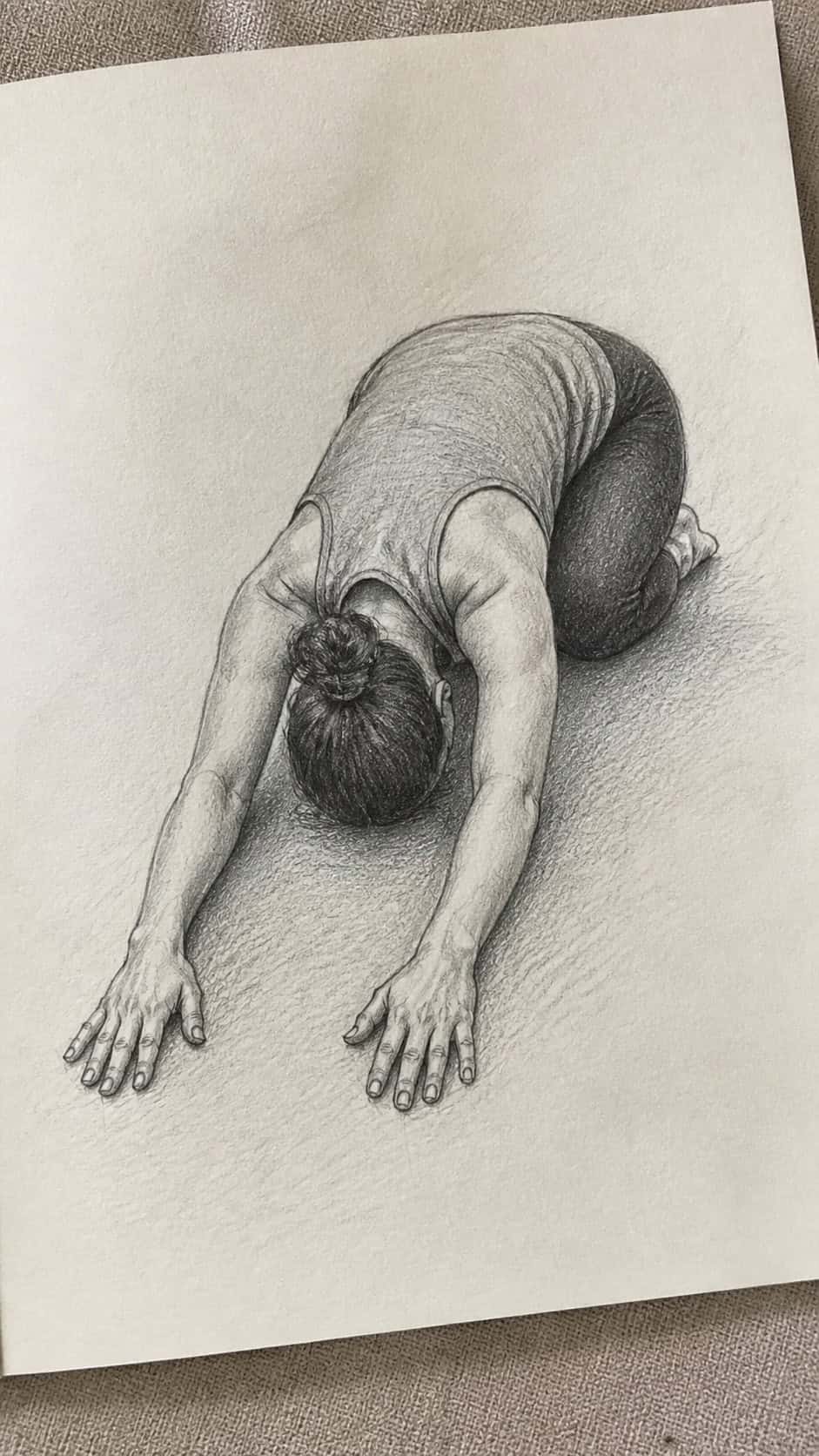 Hand-drawn playful child's pose in graphite drawing on textured paper, shown in a gentle oblique desk view that shows paper tooth and — study 2