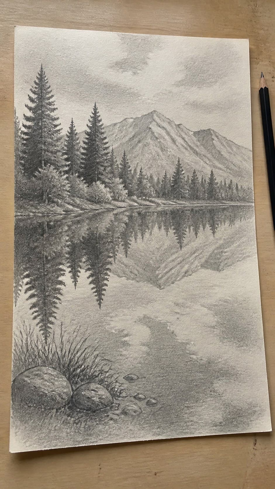 Hand-drawn serene lake reflection in graphite drawing on textured paper, shown in a slightly off-center overhead composition, like an — study 2