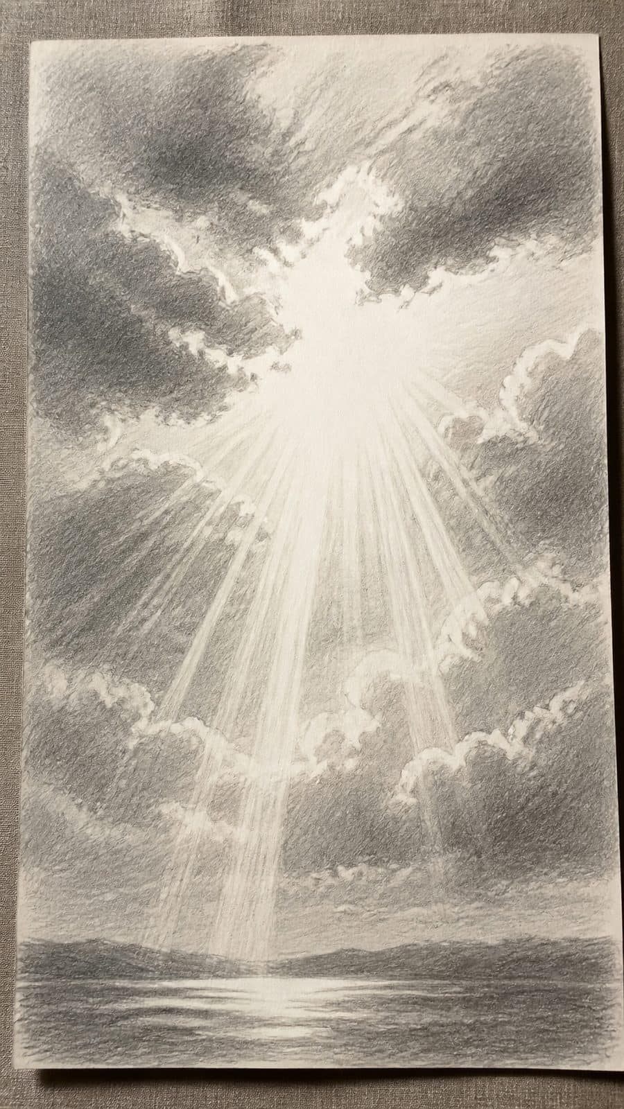 Hand-drawn divine light in graphite drawing on textured paper, shown in a slightly off-center overhead composition, like an artist — study 1