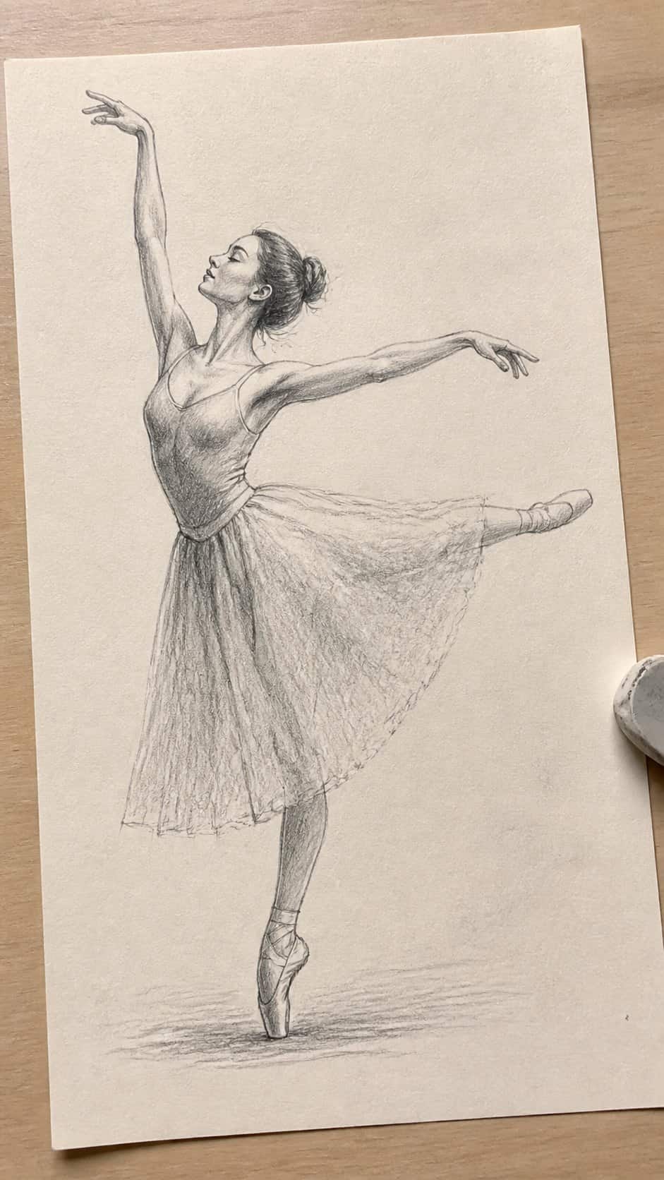 Hand-drawn graceful pose in graphite drawing on textured paper, shown in a gentle oblique desk view that shows paper tooth and shallow — study 1