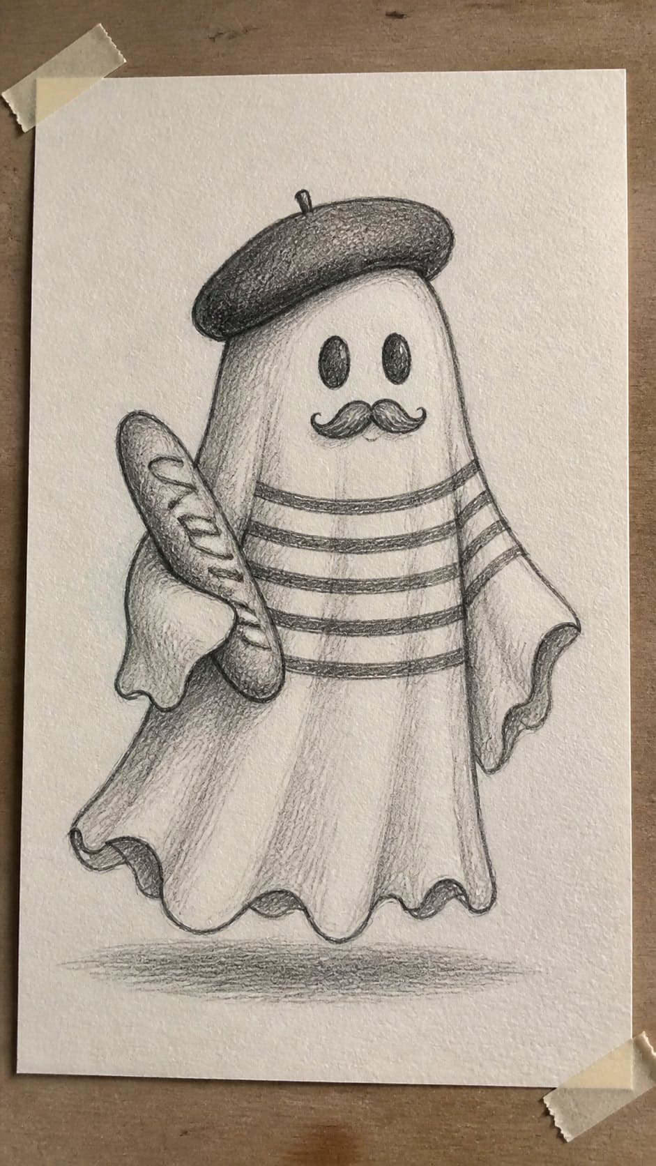 18 Ghost Drawing Ideas for Spooky and Expressive Sketches 18 Hand-drawn french ghost with a beret in graphite drawing on textured paper, shown in a gentle oblique desk view that shows paper tooth — study 1