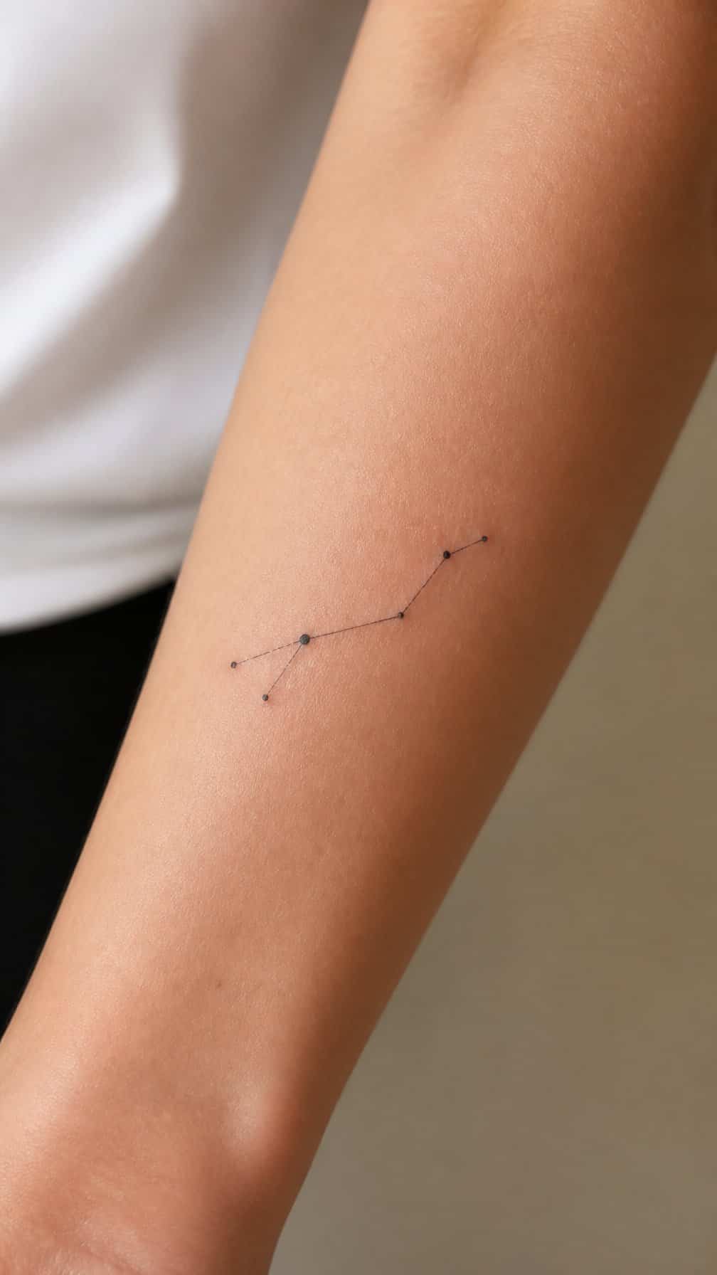 Close-up of a forearm with a delicate constellation tattoo made of fine black lines and dots.