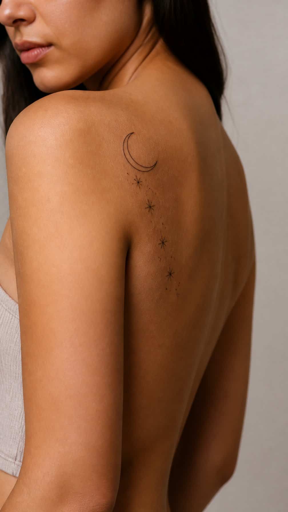 A person displays a crescent moon and stars tattoo on their shoulder and upper arm.