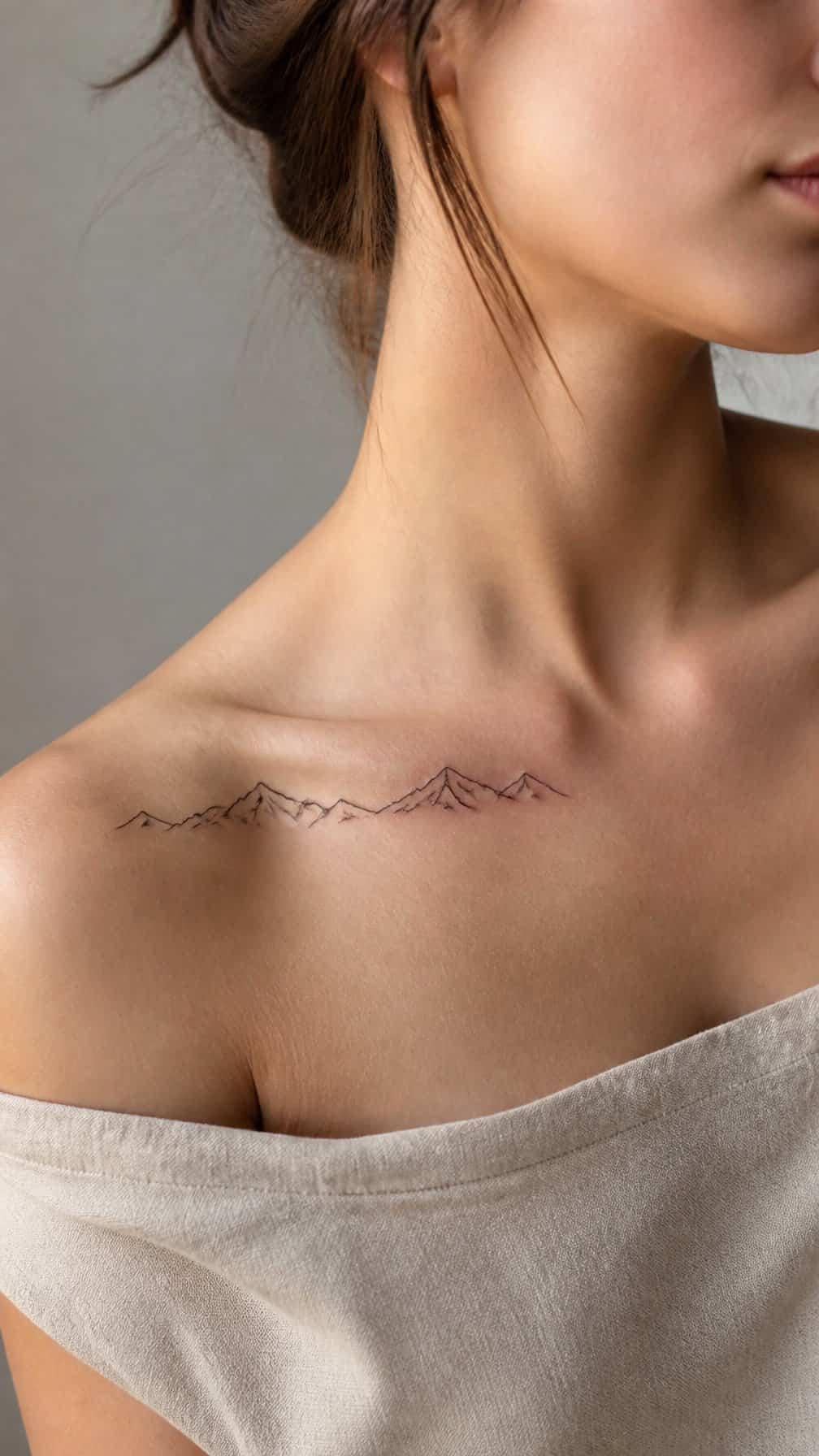 A person with a delicate mountain range tattoo along one side of the collarbone.