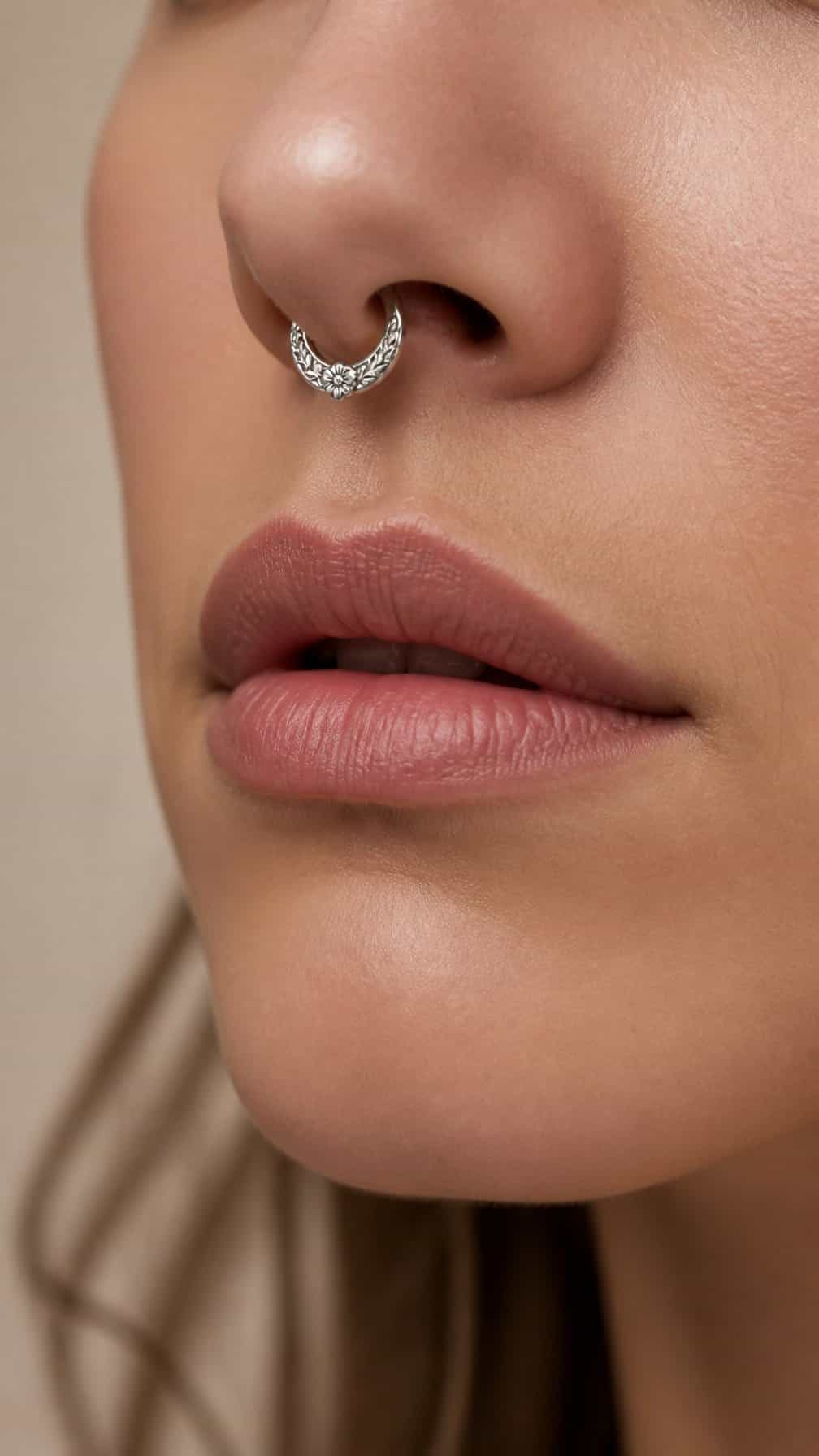 Close-up of an adult wearing a floral engraved septum ring.